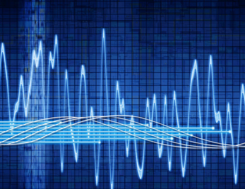 An abstract image of multiple overlaid and oscillating frequency waveforms in blue against a dark blue grid background, representing the concept of frequency stability in oscillators.